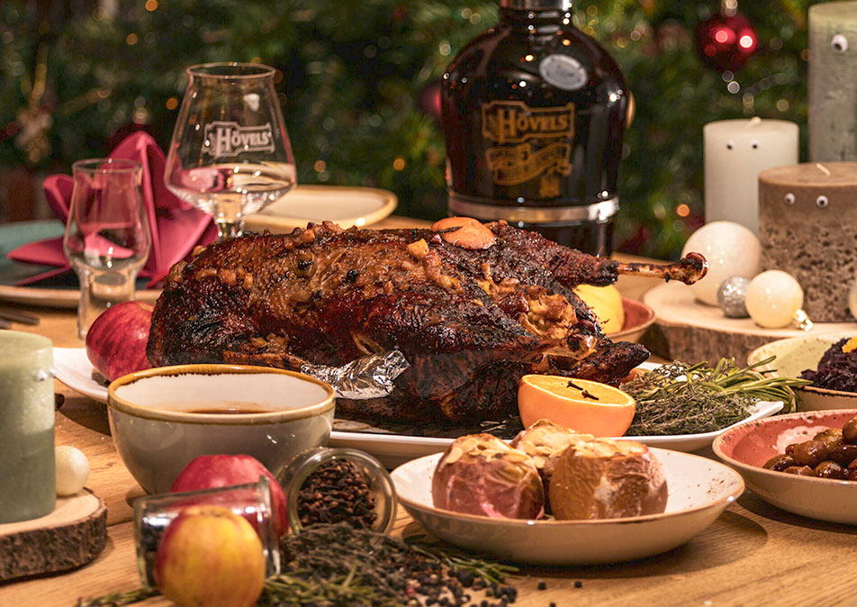 Ein festlich gedeckter Tisch zeigt eine knusprige Ente umgeben von Beilagen. Weihnachtliche Dekoration und Kerzenlicht schaffen eine gemütliche Atmosphäre.