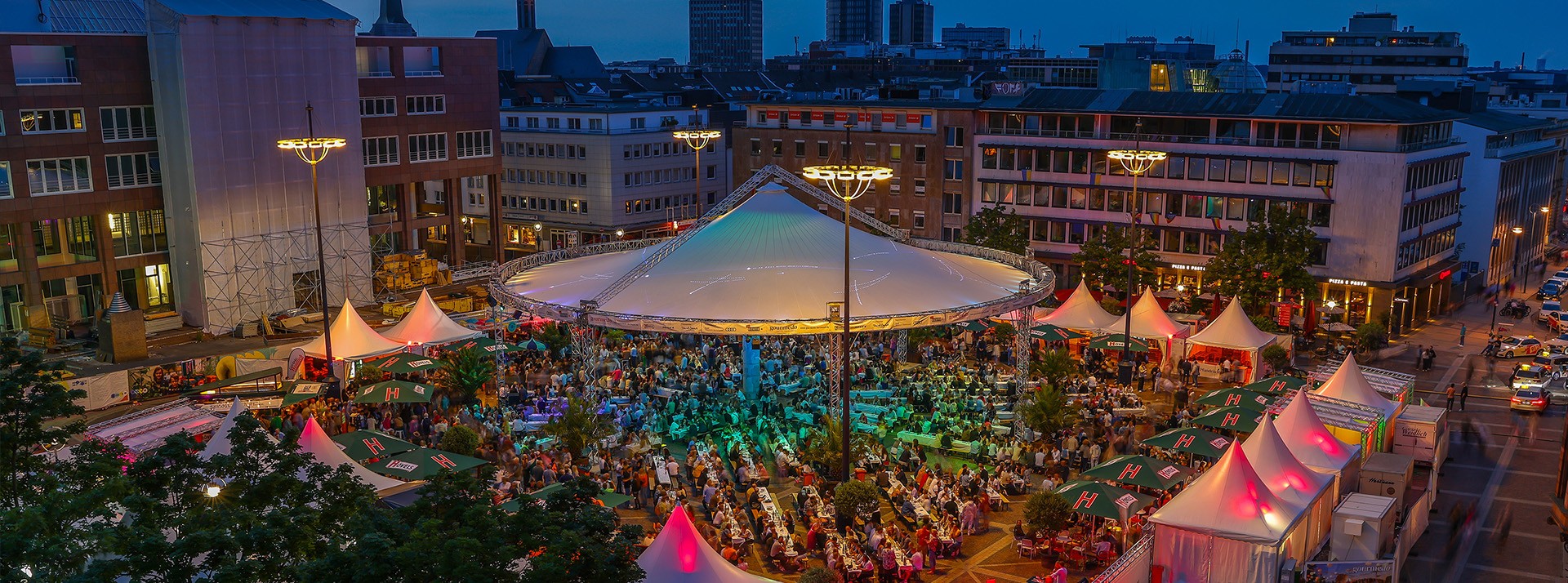 Abendliche Ansicht eines belebten Festes in der Stadt mit Zelten und vielen Menschen.