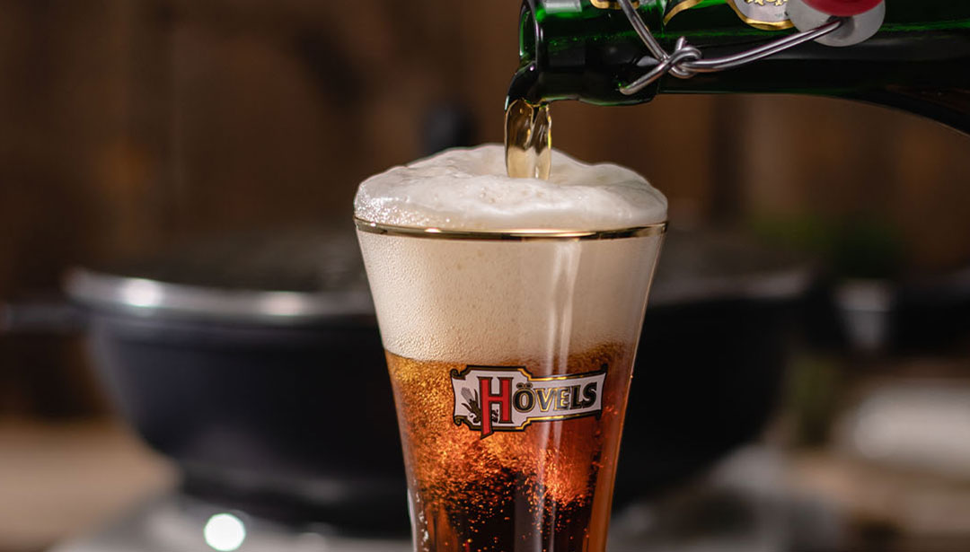 Bier wird in ein Glas gegossen und schäumt über.